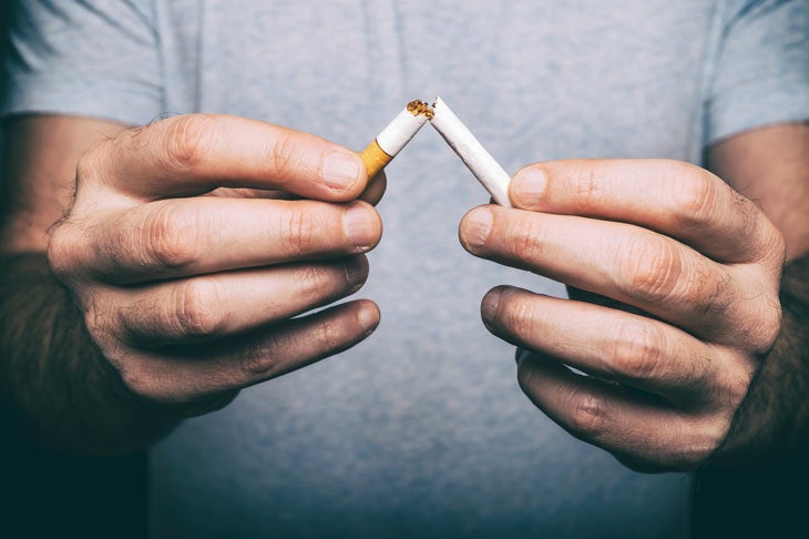 Man breaking apart a cigarette
